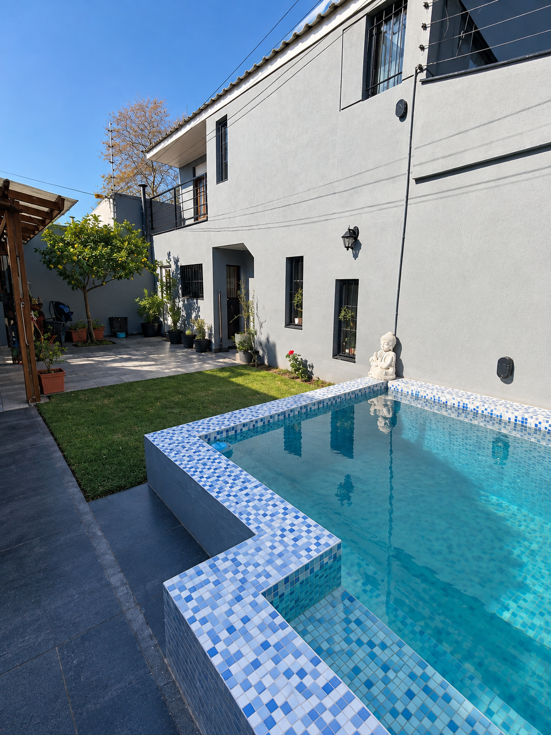 Jardín con pileta, limonero y pérgola en una vivienda de dos plantas